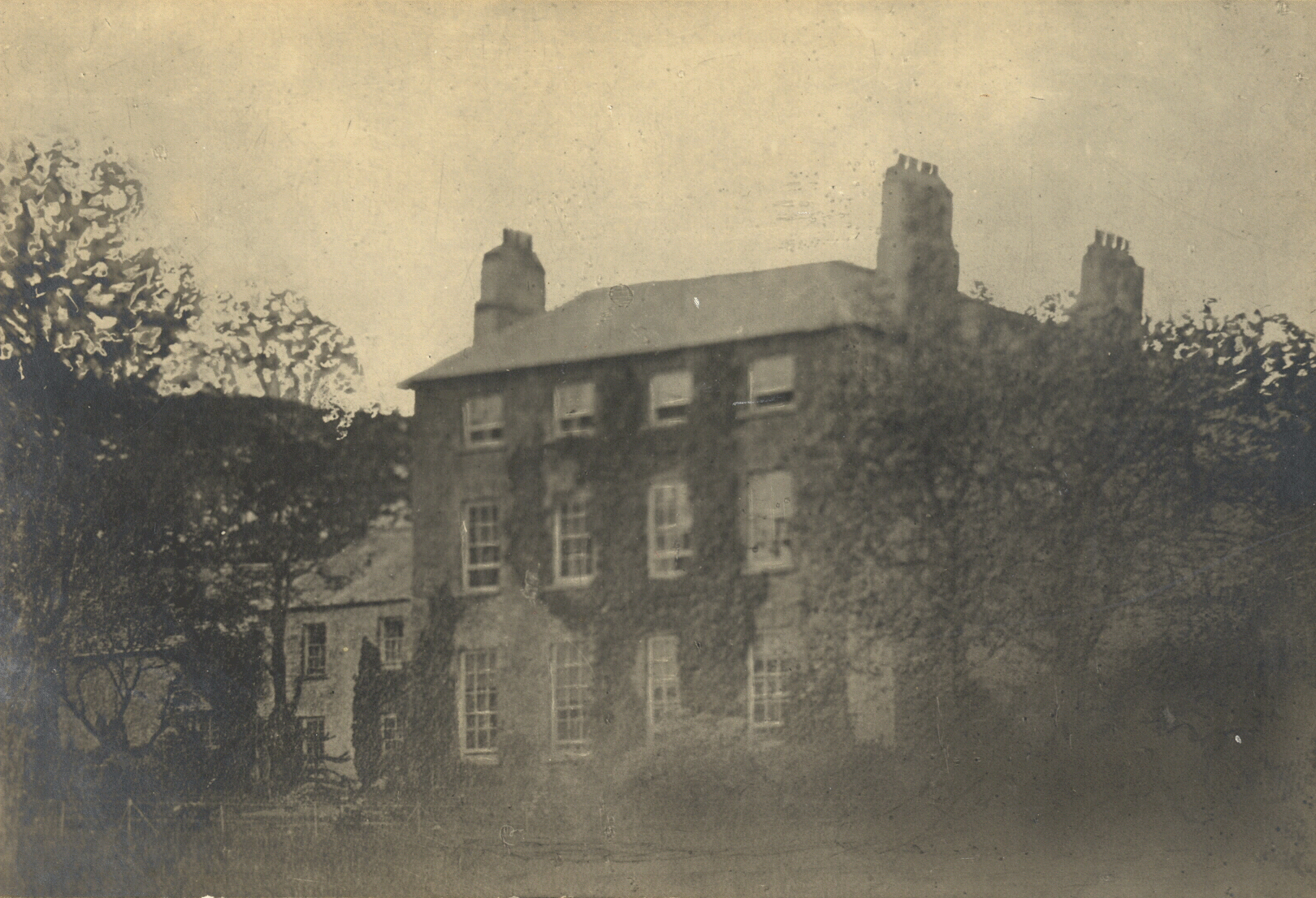 A three story house with four windows on each floor next to a smaller 2 story dwelling.